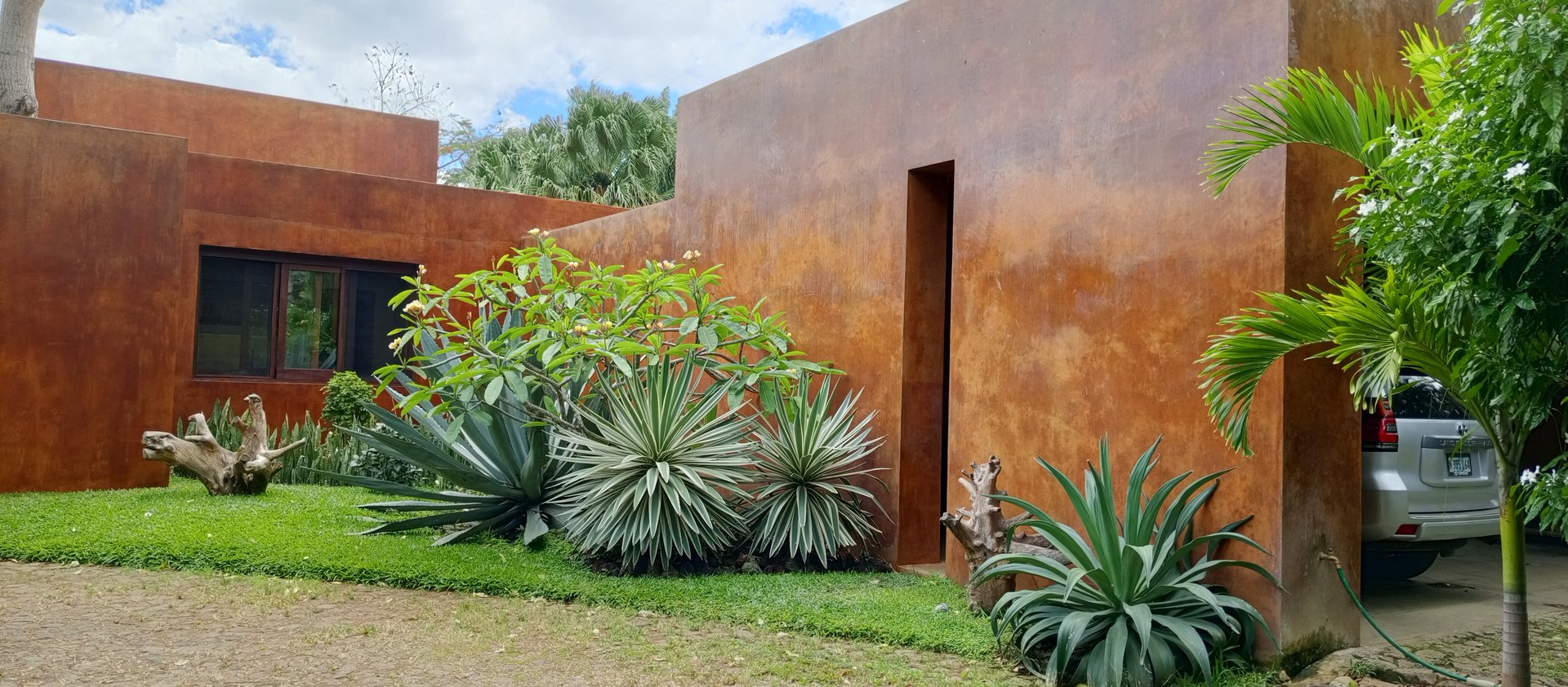 Vista de muros de estuco terracota junto a un jardín