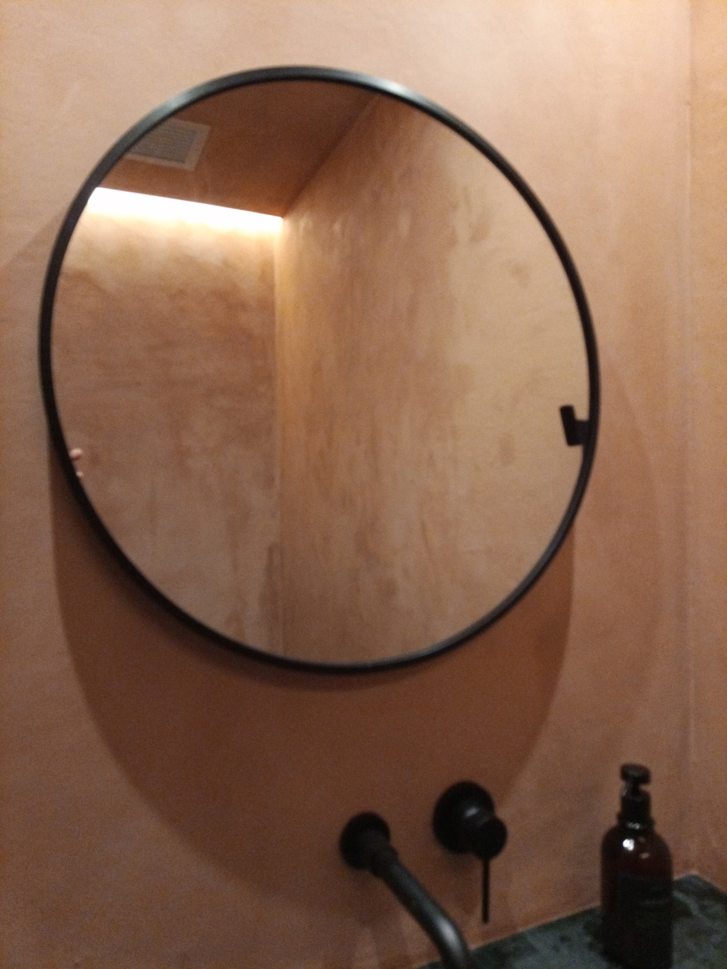 Detalle de pared de estuco junto a un espejo circular